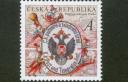 Foto 01 - Nejkrásnější známka světa - Poštovní muzeum - Hlavním motivem předlohy ke známce je rakousko-uherský vývěsní poštovní štít ze sbírek Poštovního muzea, okolo kterého se soustředí poštovní šotkové se symboly historie i současnosti poštovnictví (obálky na dopisy, poštovní razítko, poštovní roh). Pozadí známky vyplňuje stará poštovní mapa.